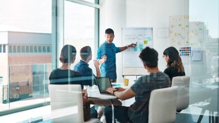 Equipo de trabajo revisando la estrategia de su negocio frente a un pizarrón